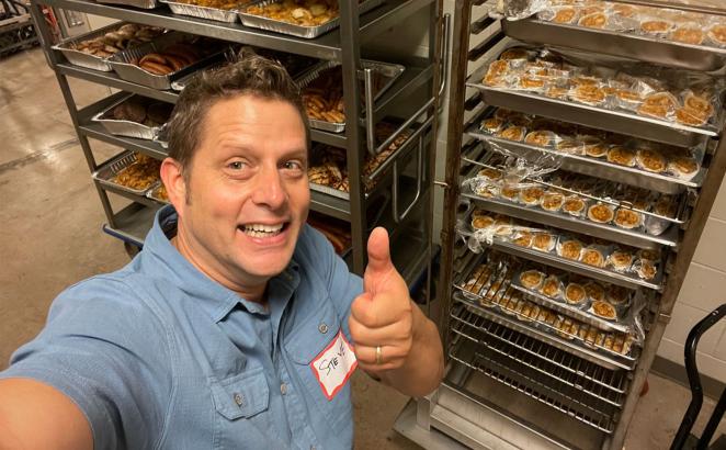man standing in front of racks of baked goods