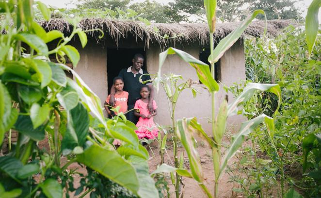 family in doorway of a grass-roofed house