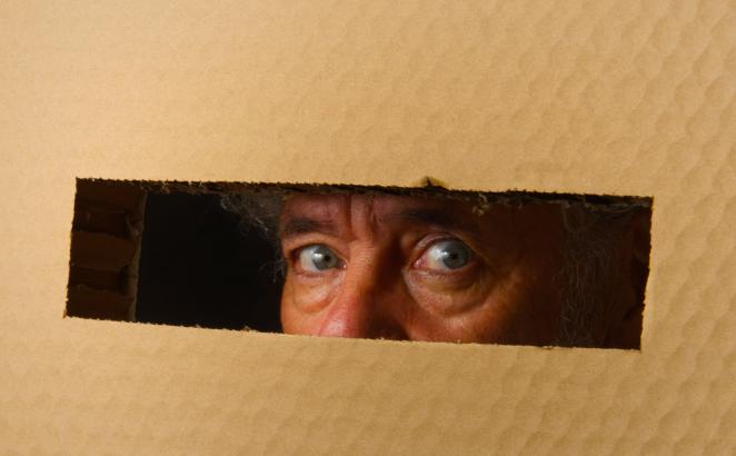 man looking through cut slot of worry box
