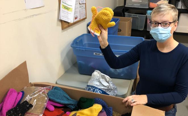 A volunteer at New Life CRC’s Clothing Closet ministry holds up a hand-knitted pair of mittens that were part of a large donation last fall.
