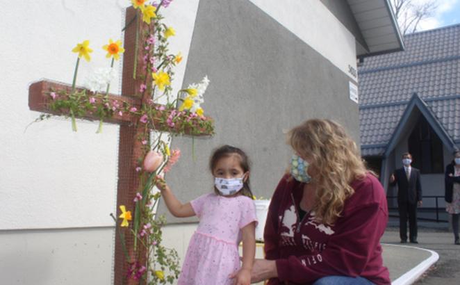 Church members Helle Colyn and granddaughter, Robin, place flowers on the cross at Alberni Valley CRC. 