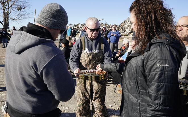 Members of three churches whose buildings were heavily damaged in the Dec. 10 storm joined together for a service, Sunday, Dec. 12, in the parking lot of First Christian Church in Mayfield, Ky. Jim Heath (center) an elder with the church served communion to the worshipers.