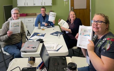 group of people around a table holding up booklets