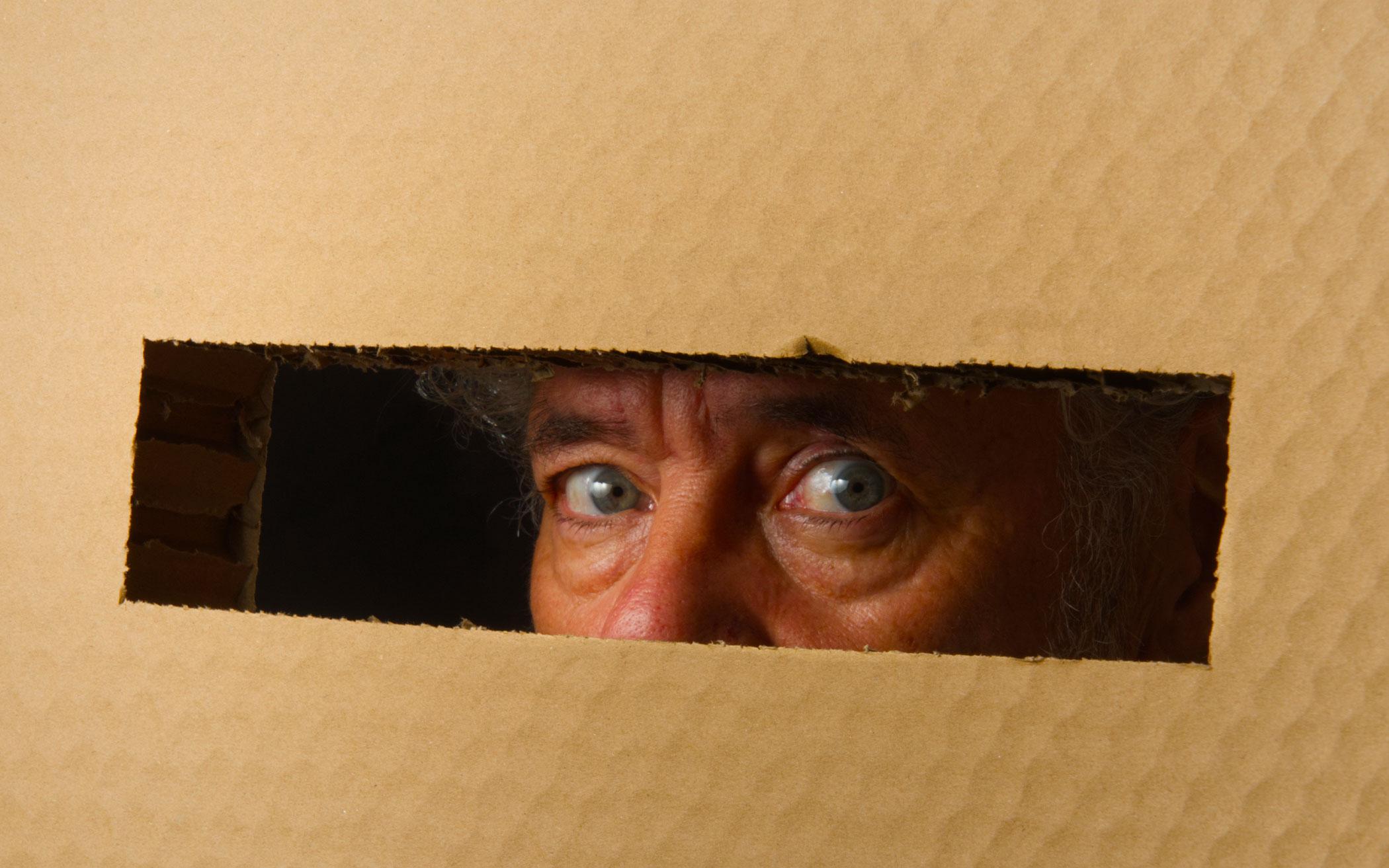 man looking through cut slot of worry box