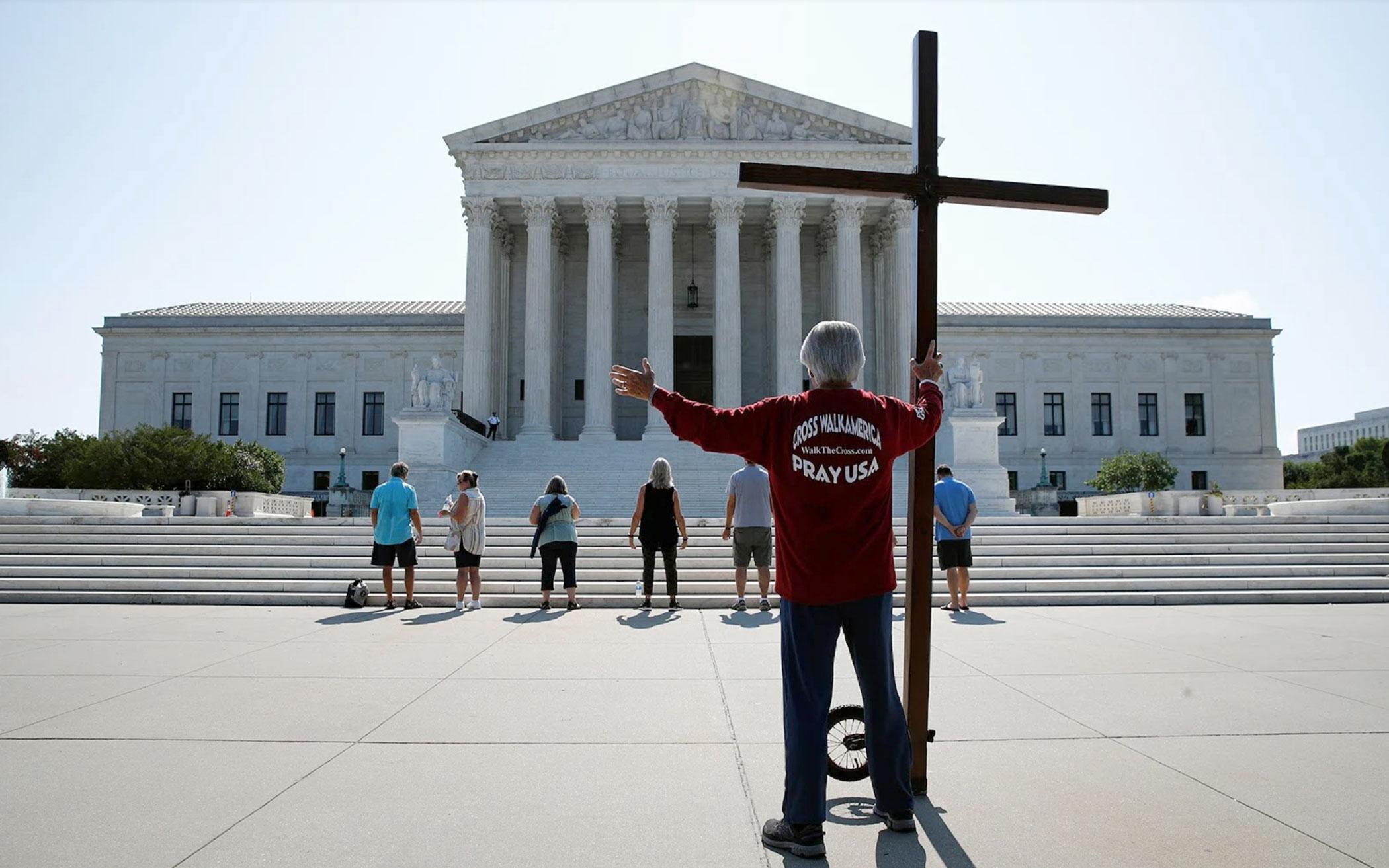 Tom Alexander holds a cross as he prays prior to rulings outside the Supreme Court on Capitol Hill in Washington on July 8, 2020.