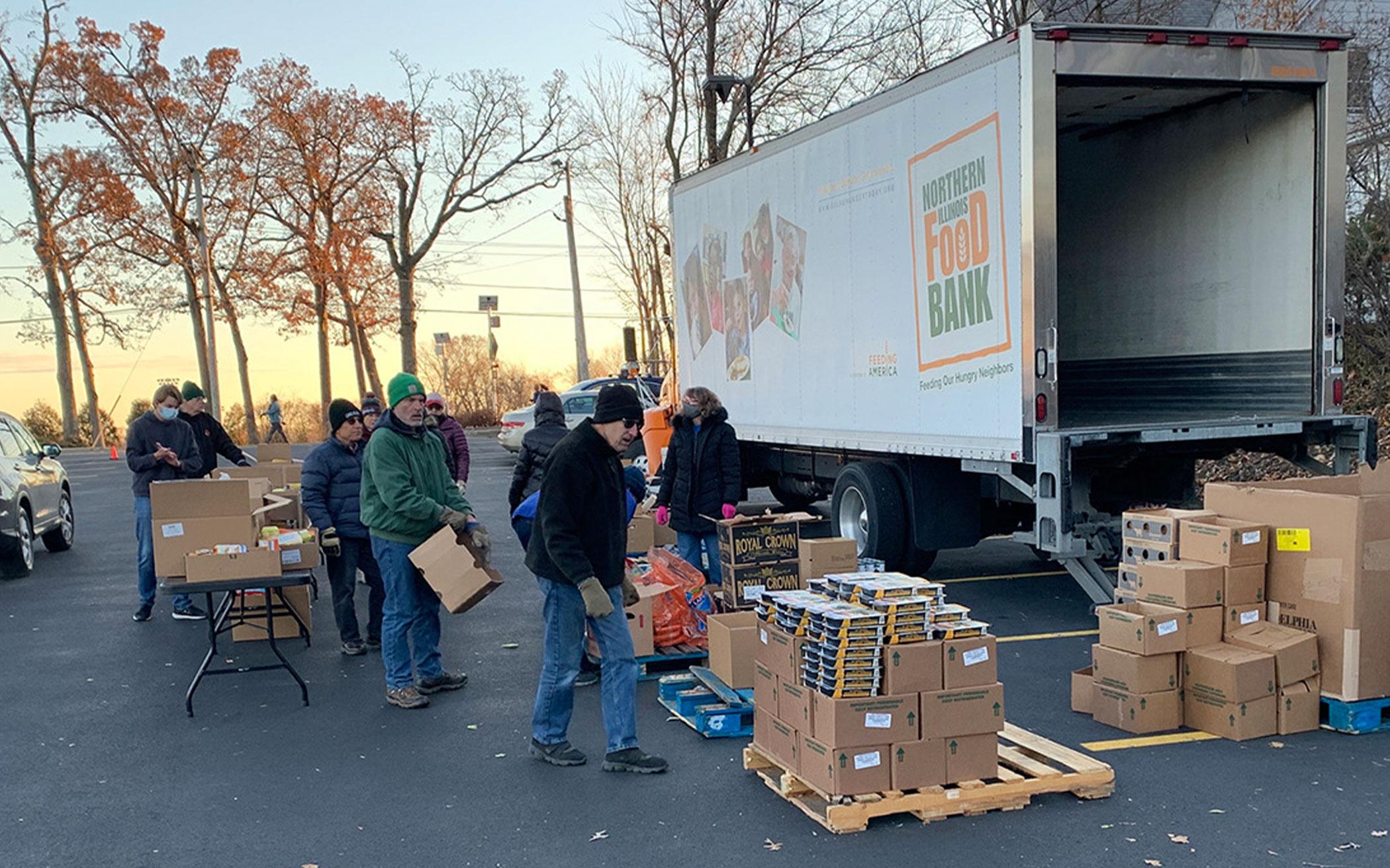 Volunteers unload a Northern Illinois Food Bank truck for distribution in a parking lot of St. Anne’s Episcopal Church in Woodstock, Ill., Nov. 22, 2021.

