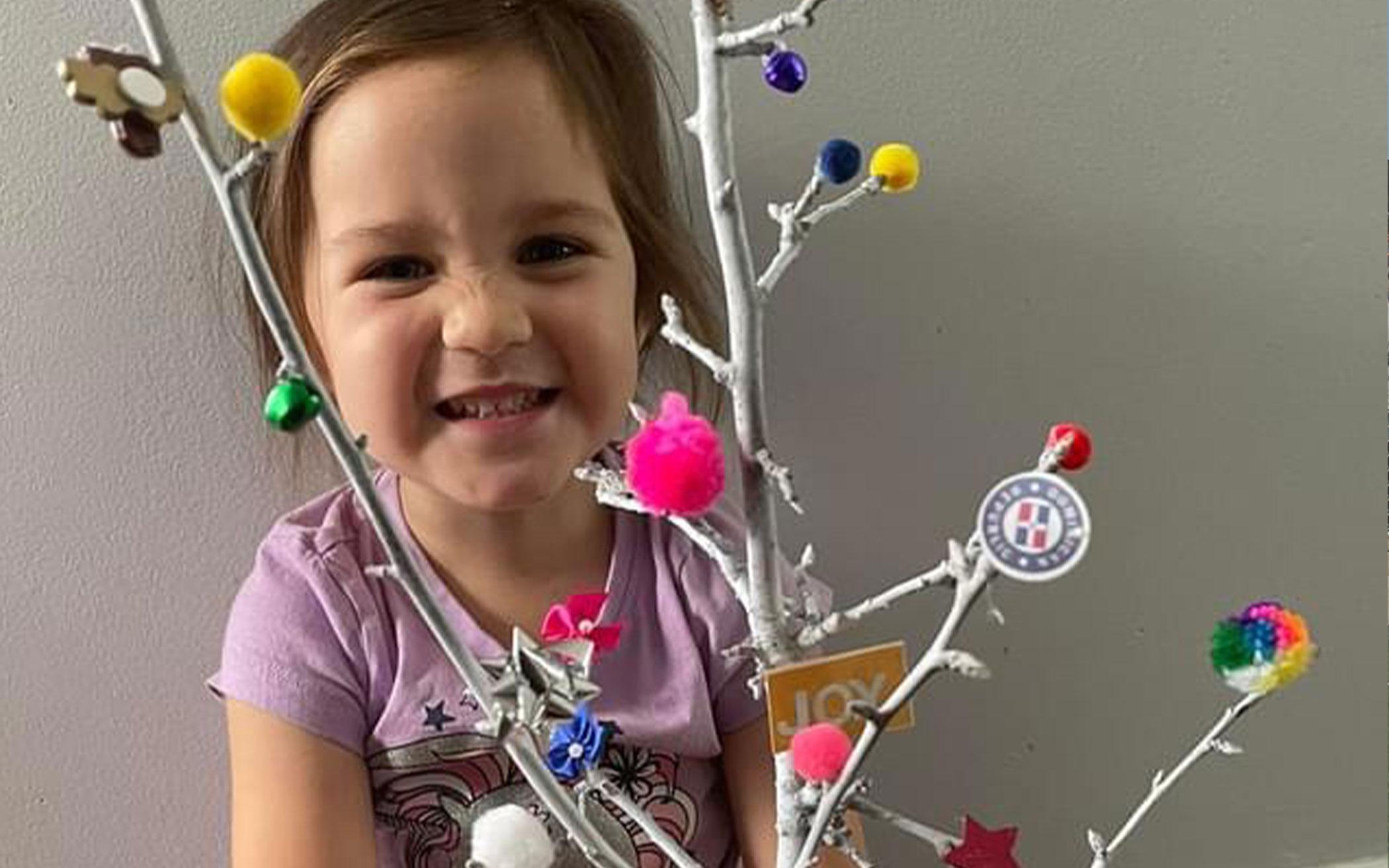 Naomi, 3, with the Charamico tree, a craft for the Dominican Republic Advent celebration week.