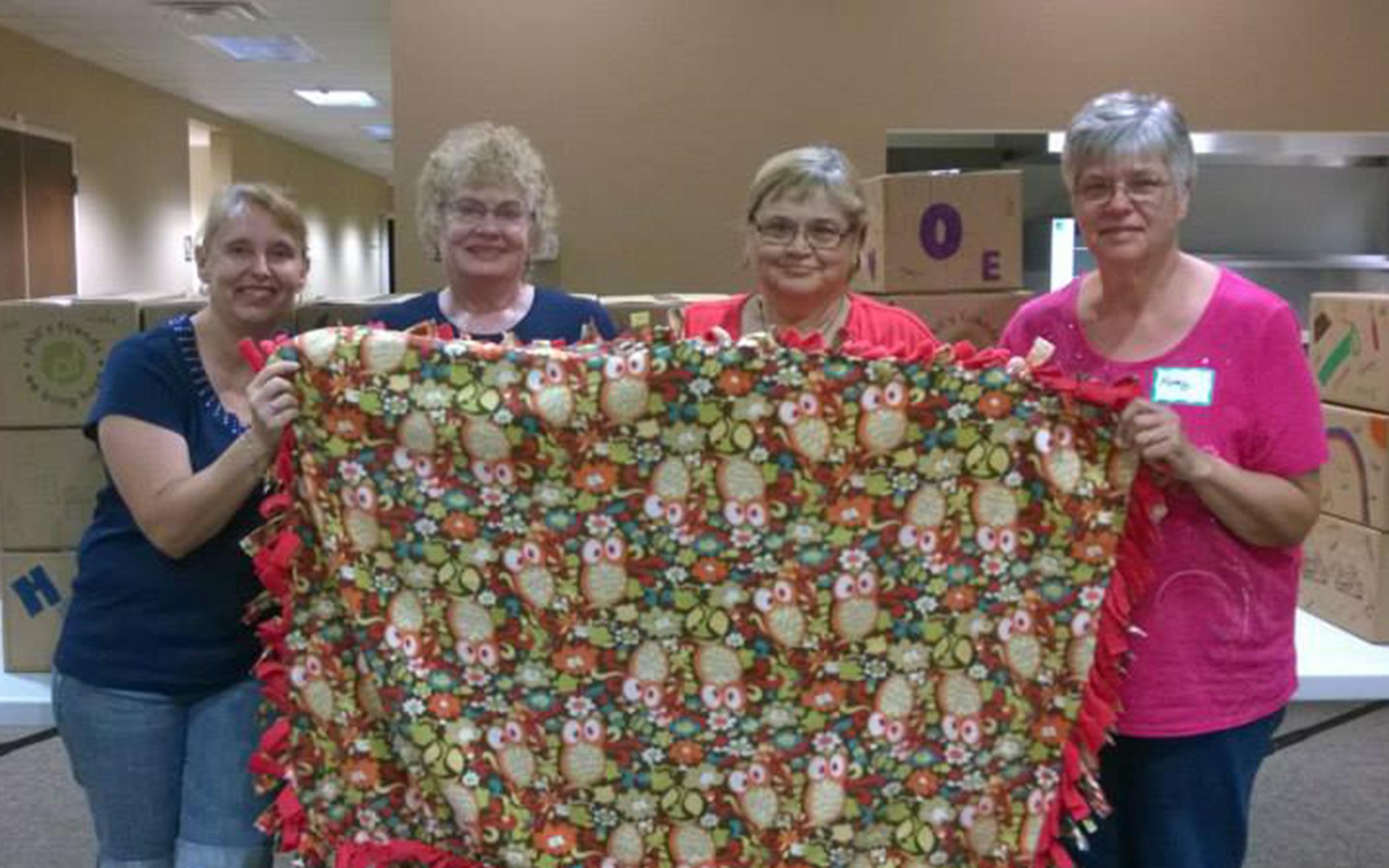 Tracy Szczudlak (left) holds a blanket with three other volunteers at Community CRC.
