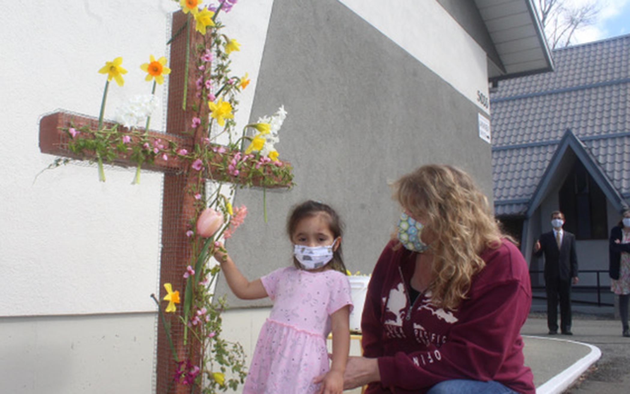 Church members Helle Colyn and granddaughter, Robin, place flowers on the cross at Alberni Valley CRC. 