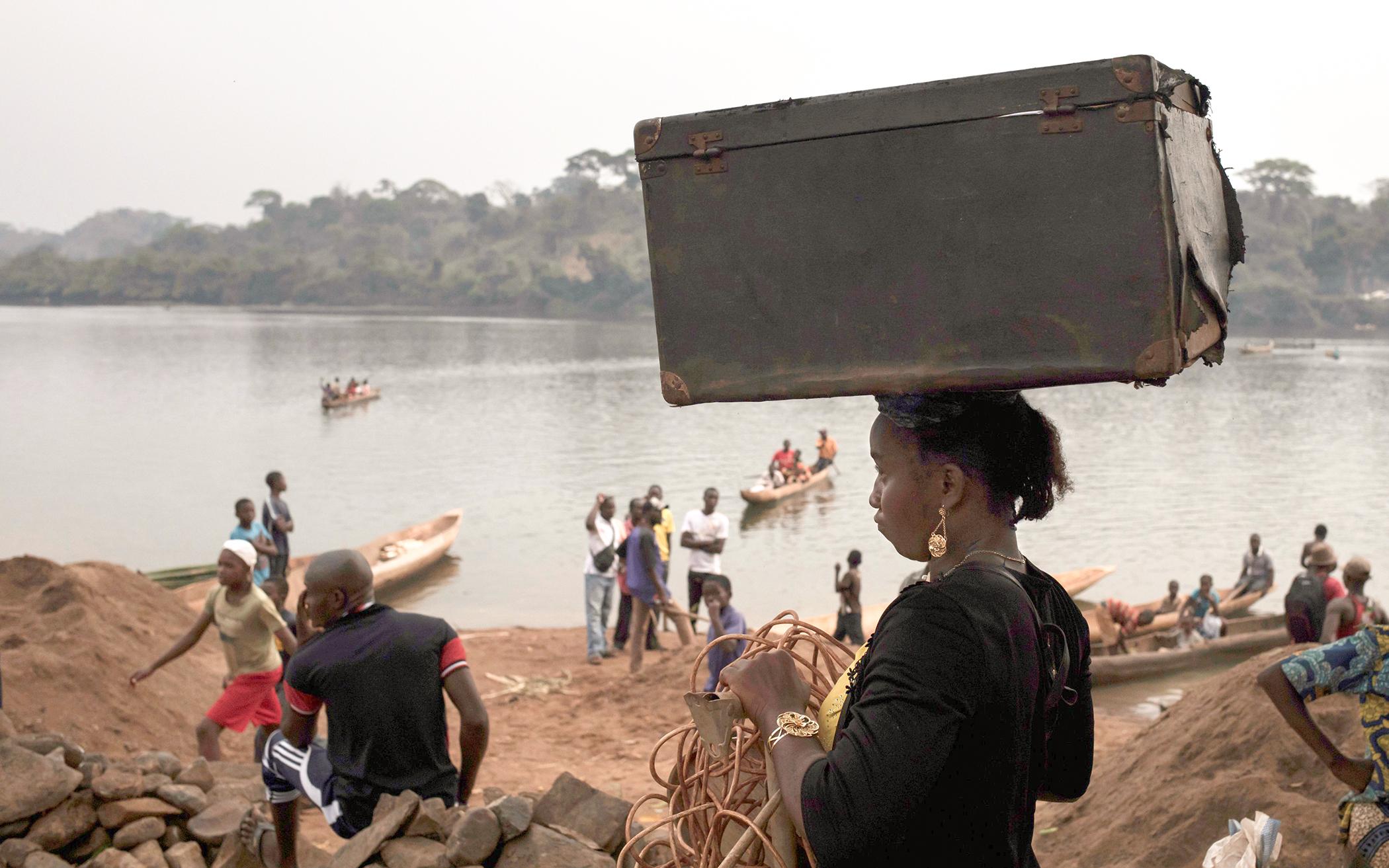 A woman carries her belongings back into Bangassou, Central African Republic, from Ndu in the Democratic Republic of the Congo, where she had taken refuge, Feb. 14, 2021. An estimated 240,000 people have been displaced in the country since mid-December, according to U.N. relief workers.