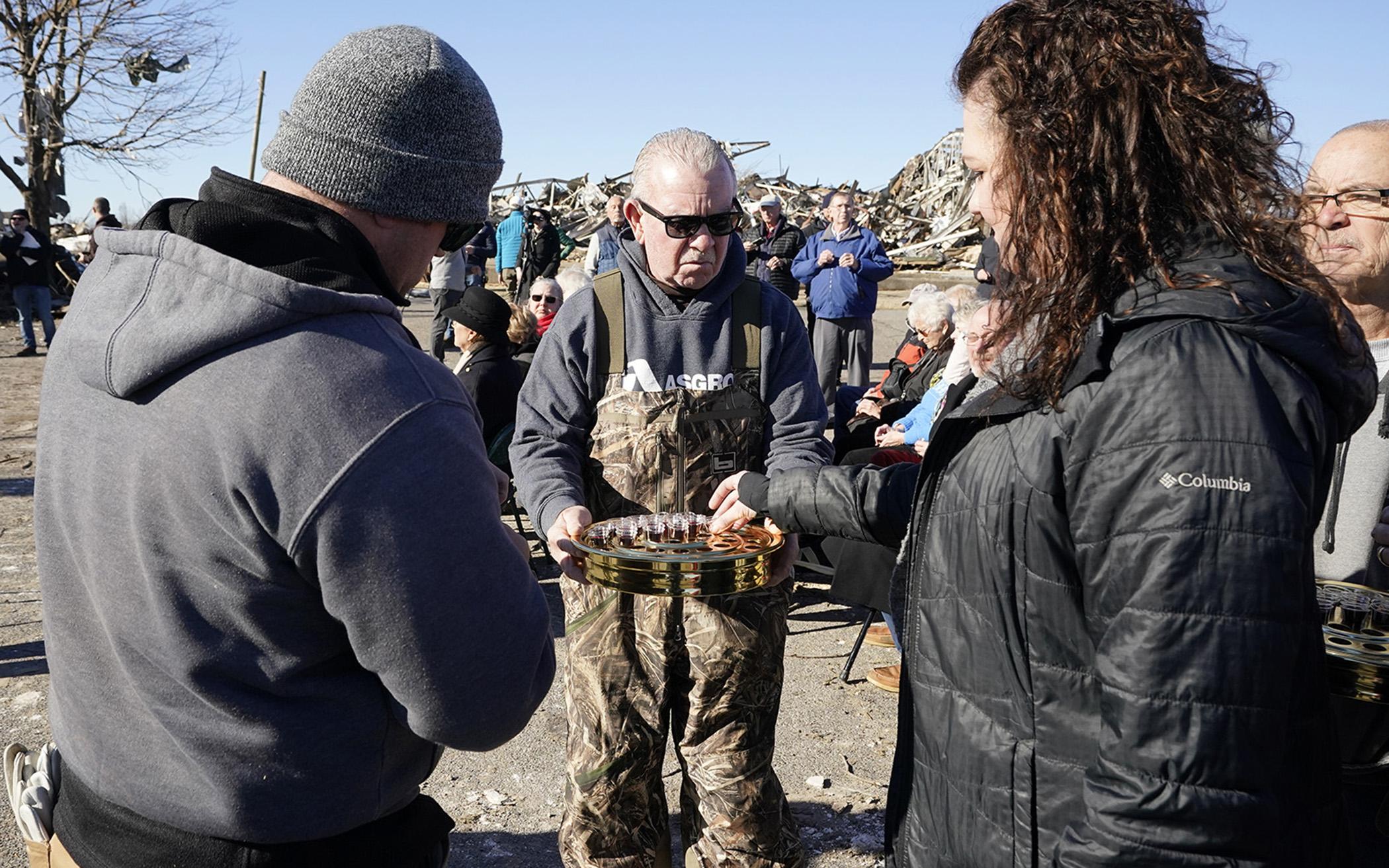 Members of three churches whose buildings were heavily damaged in the Dec. 10 storm joined together for a service, Sunday, Dec. 12, in the parking lot of First Christian Church in Mayfield, Ky. Jim Heath (center) an elder with the church served communion to the worshipers.