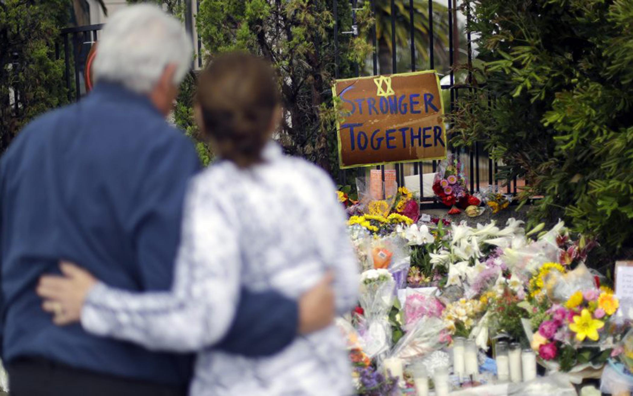 A couple embrace near a growing memorial across the street from the Chabad of Poway synagogue in Poway, Calif., on April 29, 2019. A gunman opened fire, killing one person, on April 27, 2019, as about 100 people were worshipping. The attack happened exactly six months after a mass shooting in a Pittsburgh synagogue.